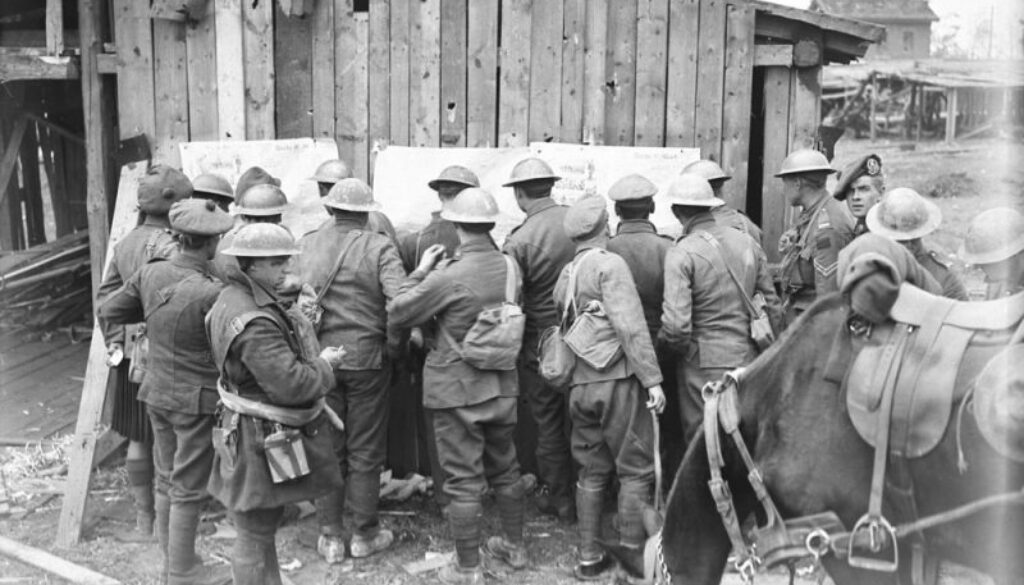 239_Canadians in front area reading the news from newspapers pinned up on German hutment out of which the Germans have just been pushed. Advance East of Arras. Oct. 1918.