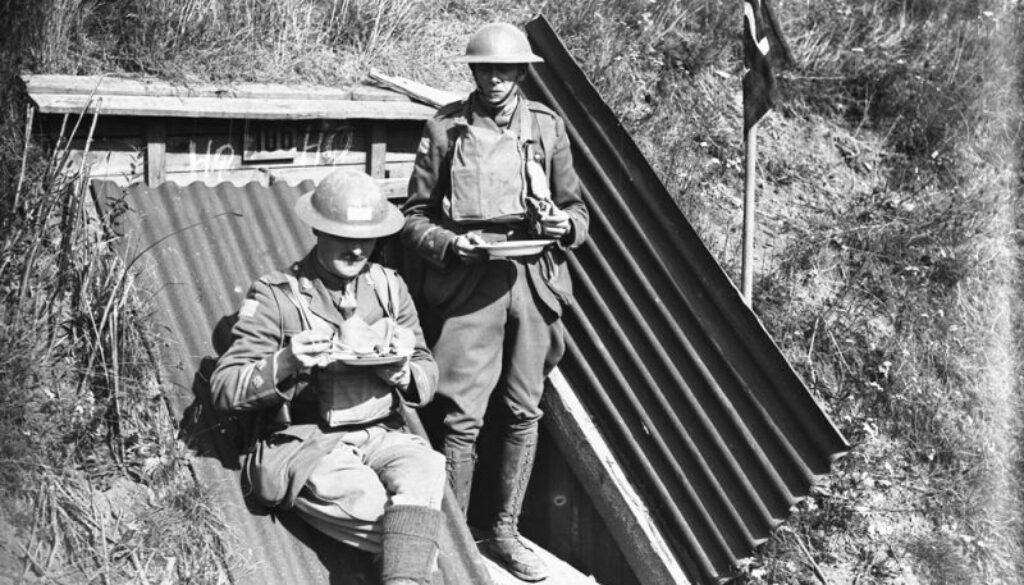 Two officers of the Canadians having a hurried meal outside a German dug-out. Advance East of Arras. September, 1918.